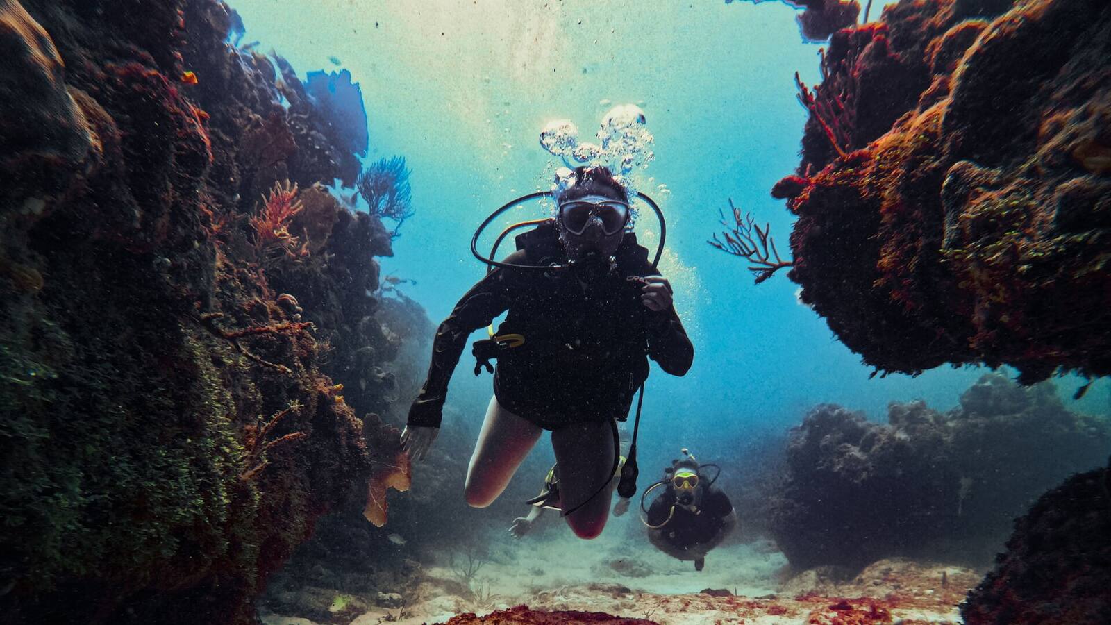 Buceadora entre paredes de coral en un cañón del arrecife de la Riviera Maya